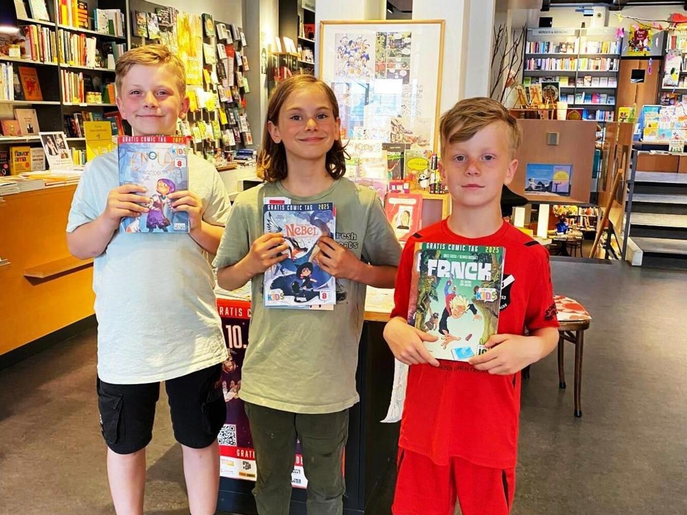 "Moritz und Freunde beim Gratis-Kids-Comictag in Buchhandlung Hintzen, lächelnd mit Comics in der Hand."