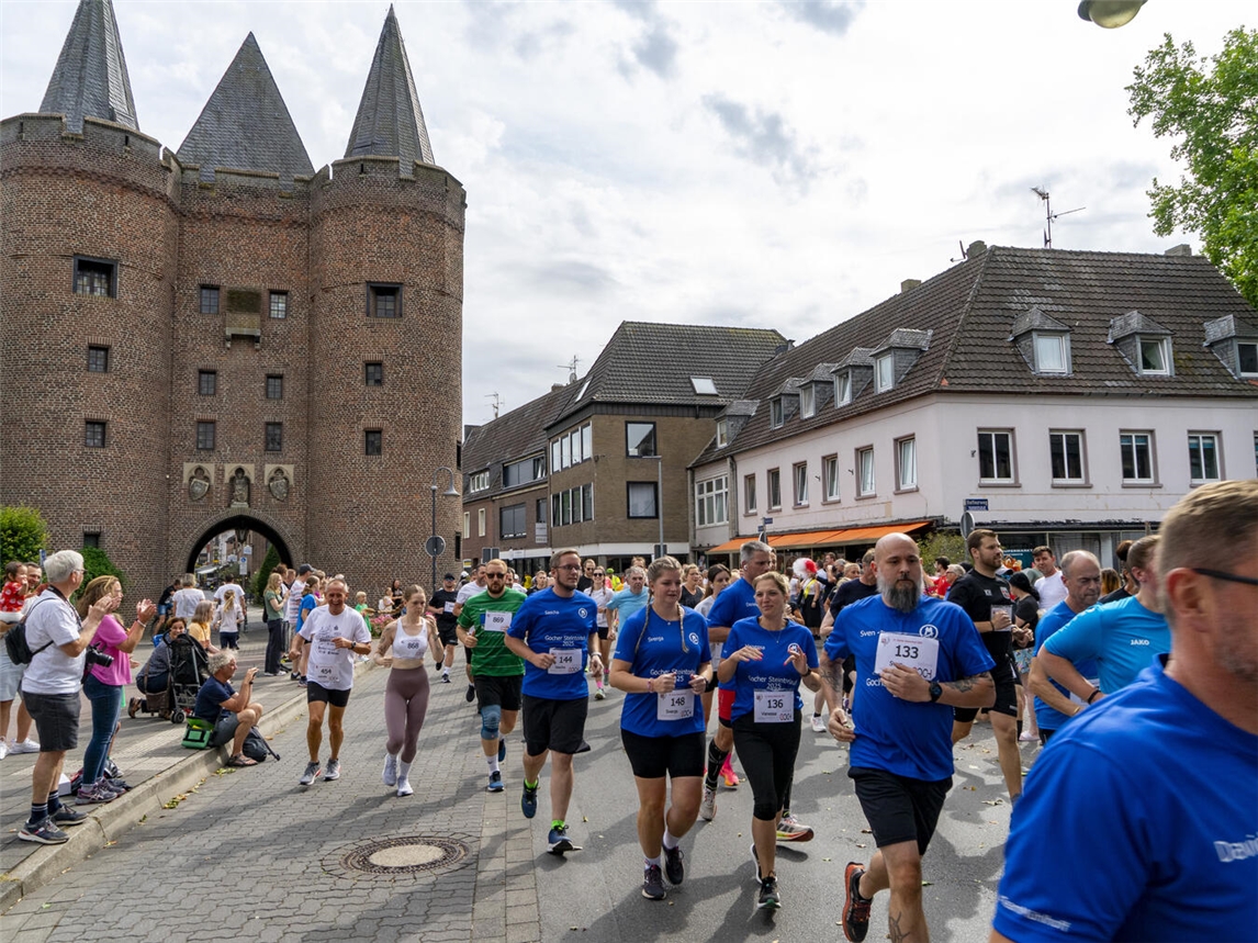 "Historisches Steintor bei Nacht, beleuchtet, mit moderner Architektur im Hintergrund"