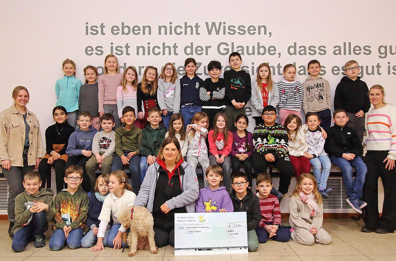 Nicole Münster vom Gelderner Tierheim kam mit Rüde „Graf“ zur Michael-Schule, um den obligatorischen Spendenscheck der Zweitklässler und ihren Klassenlehrerinnen Marie Trienekens (2a) und Stefanie Uthmann (2b) entgegenzunehmen. NN-Foto: Theo Leie
