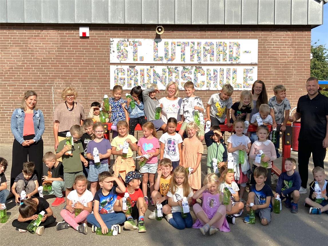 Nils Rudolph (hinten r.), Westenergie-Kommunalmanager, Bürgermeisterin Britta Schulz (hinten 2. v. l.), Ruth van de Laak, Schulverwaltung der Stadt Kalkar und die Lehrerinnen Anne Korthals (hinten Mitte) sowie Christin Noack (hinten 2. v. r.) bei der Übergabe der Trinkflaschen an einen Teil der 120 Erstklässlerinnen und Erstklässler. Foto: Westenergie AG