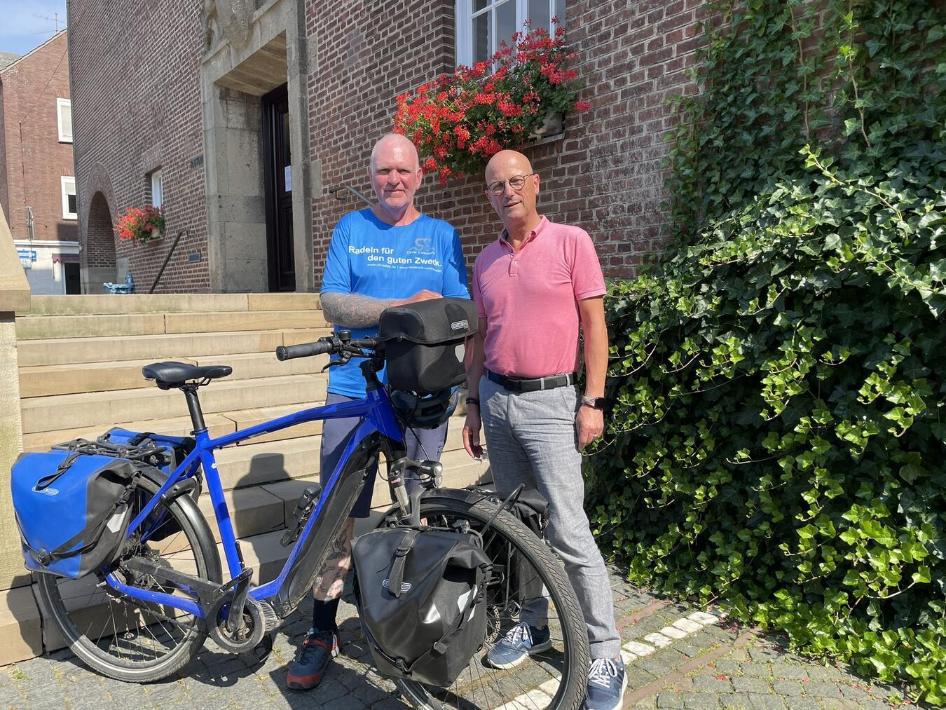 „Oli radelt“ vor dem Rathaus: Bürgermeister Peter Hinze mit Oli Trelenberg. Foto: Stadt Emmerich