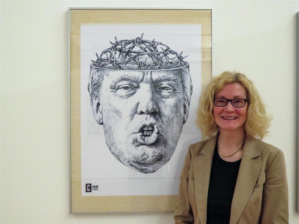 PAN-Kuratorin Christiane van Haaren mit einem Plakat zum einem Thema, mit dem sich Tomaso Marcolla intensiver beschäftigt: US-Präsident Donald Trump und dessen Grenzpolitik. NN-Foto: Gerhard Seybert