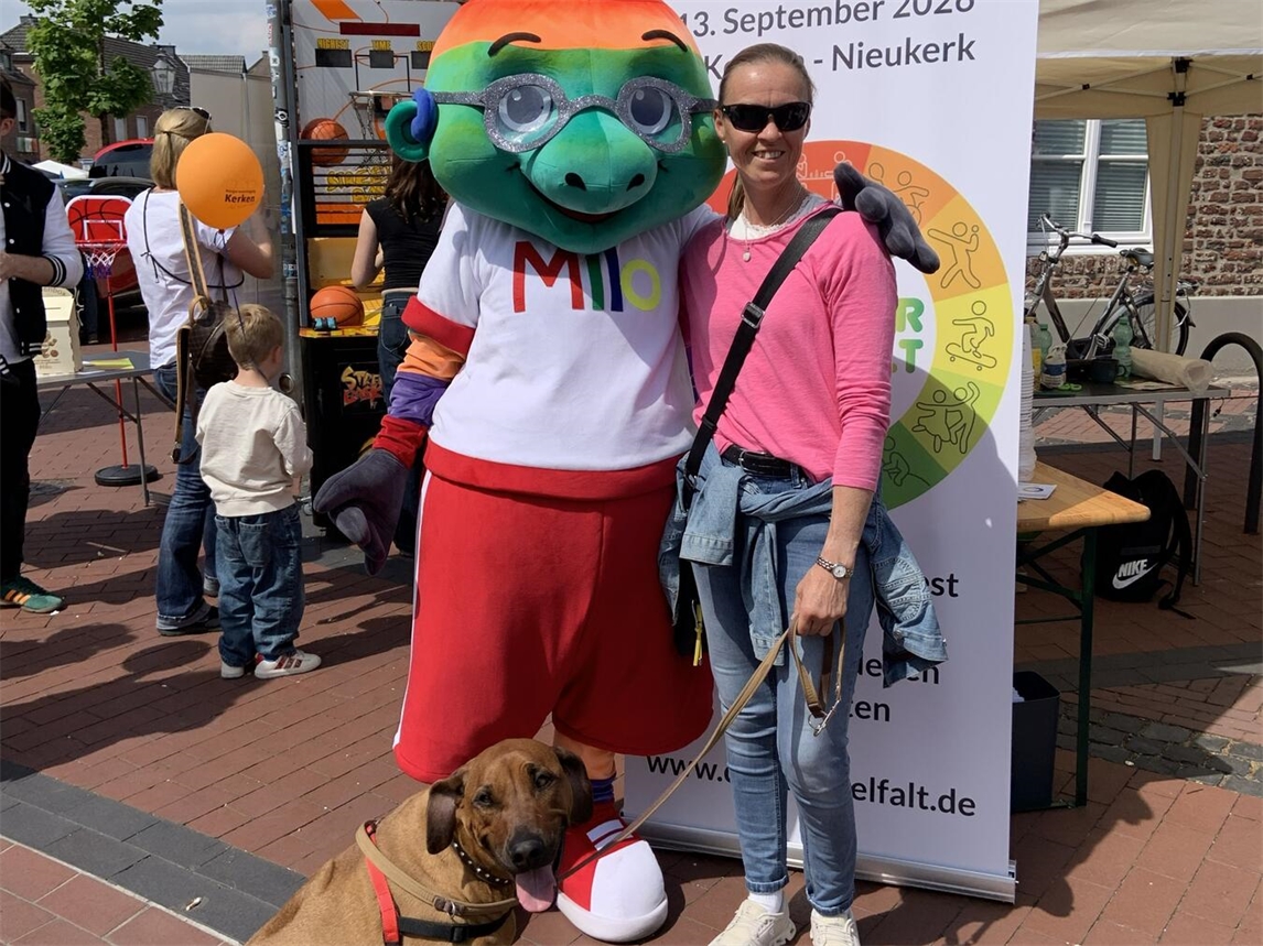 "Para-Dressurreiterin Regine Mispelkamp mit Maskottchen Milo beim Cup der Vielfalt, lächelnd in Vorfreude auf Besucher"