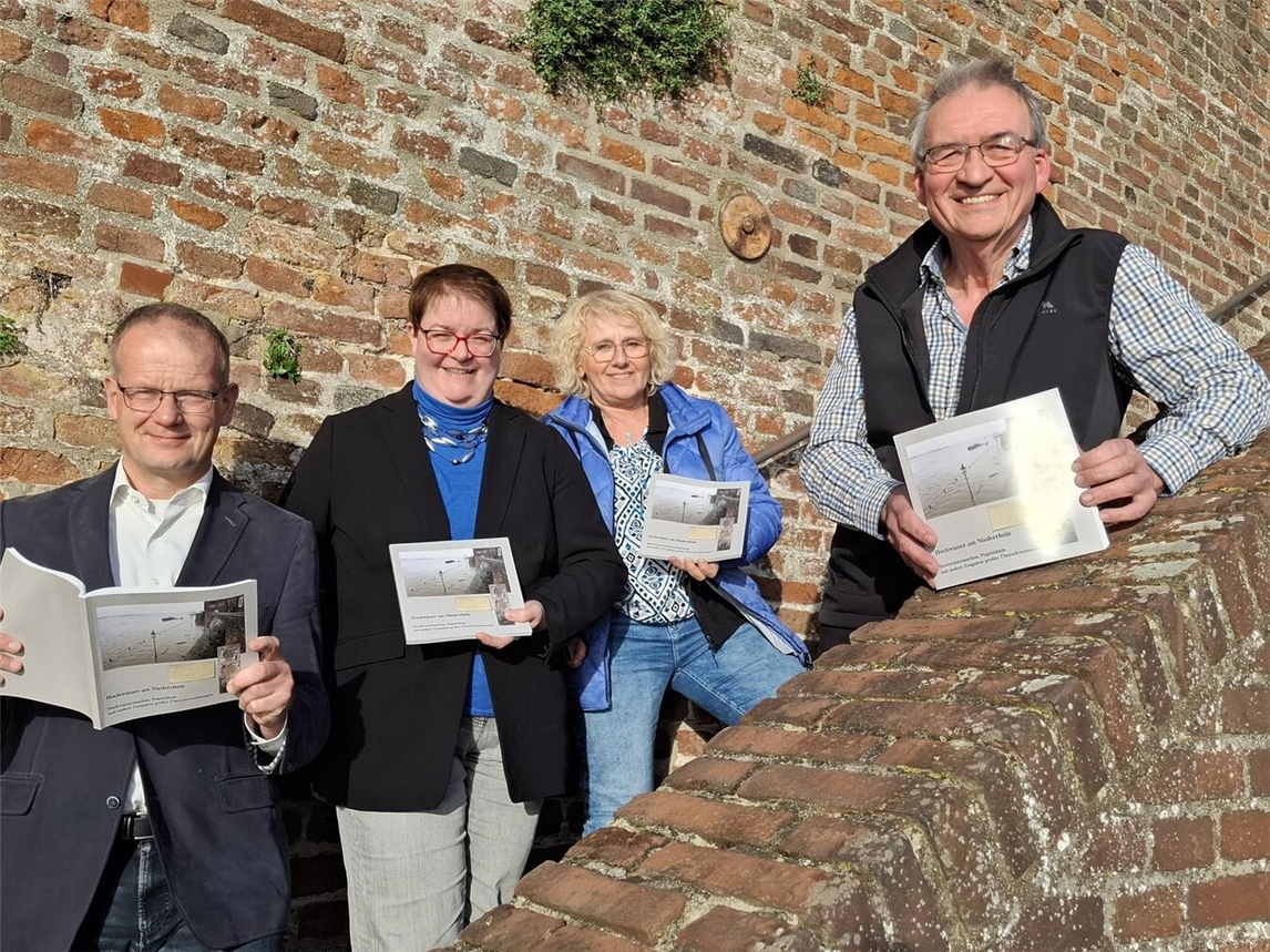 Peter von Bein (r.) stellt sein neues Buch im Beisein von Büchereileiter Thomas Dierkes, Fachbereichsleiterin Sigrid Mölleken und Stadtarchivarin Tina Oostendorp (v. li.) vor. Im Hintergrund ist eine Hochwassermarke von 1883 zu sehen. Foto: Stadt Rees