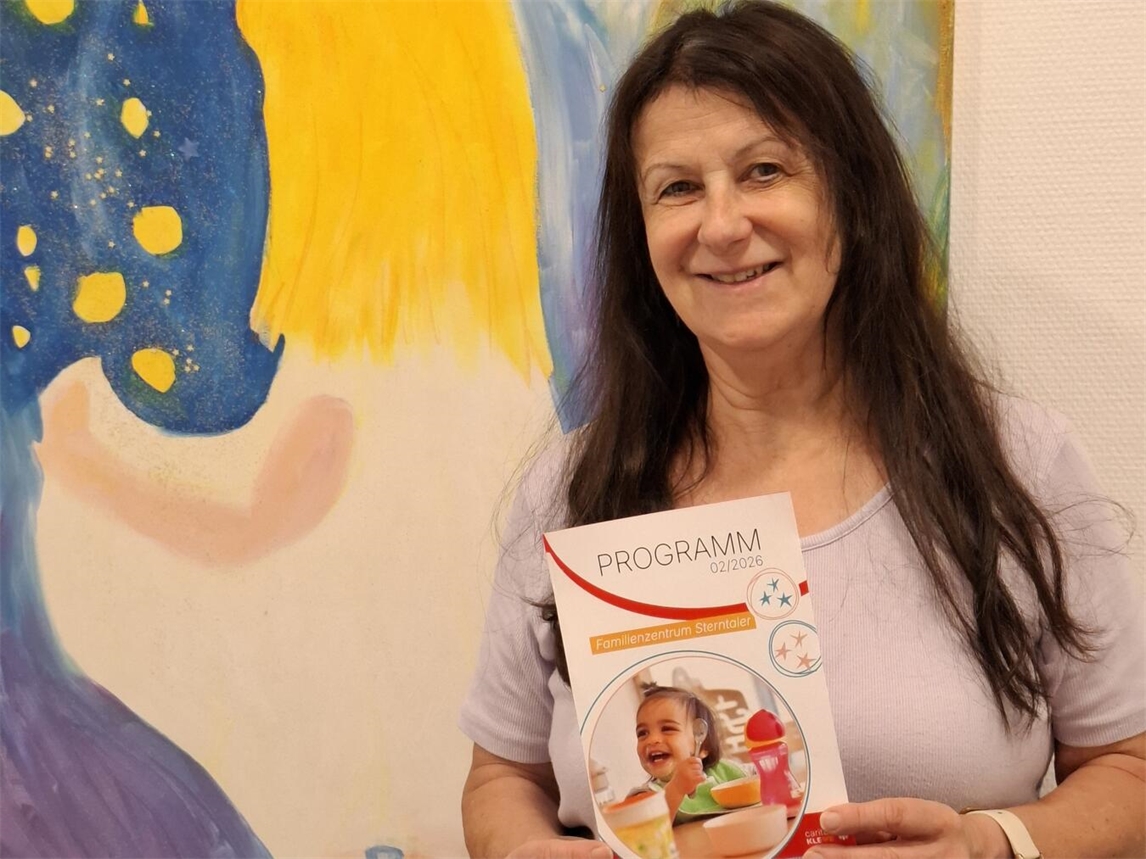 Petra Brooks hält Programmflyer für das zweite Halbjahr, lächelnd, im Freien. Foto: privat