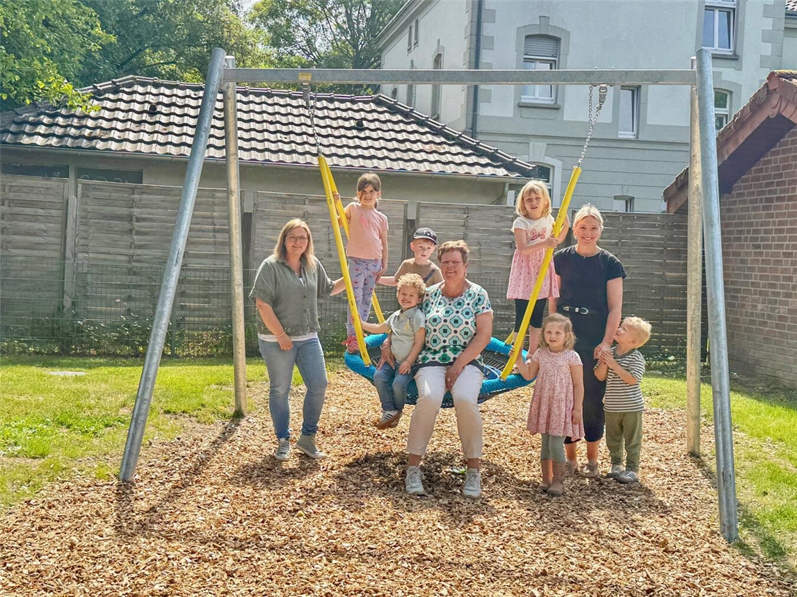 Petra Erkes und Team freuen sich mit Kindern über neue Nestschaukel im Kindergarten Zipfelmütze.