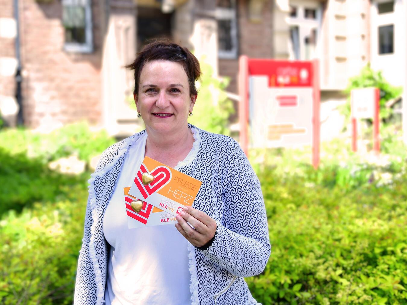 Pflege braucht Herz: Alexia Meyer, Fachbereichsleiterin Pflege und Gesundheit beim Caritasverband Kleve, wird anlässlich des Internationalen Tages der Pflegenden am 12. Mai mit ihren Kollegen Herz-Karten mit goldenem Schokoladen-Herz in der Klever Innenstadt verteilen. Foto: Caritas