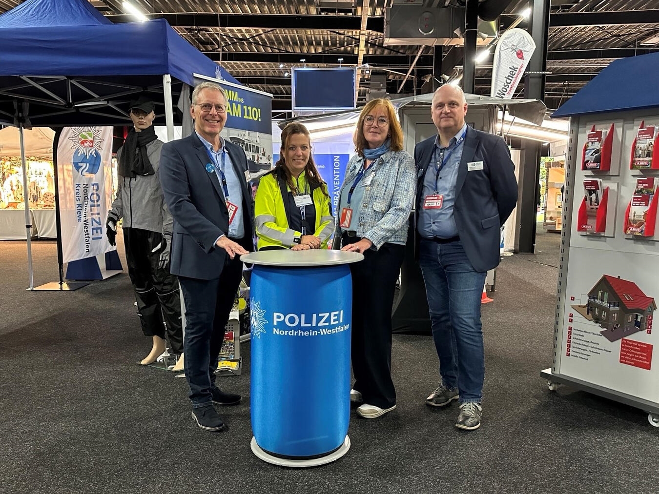 "Präventionsstand auf Wochenmarkt mit Informationsmaterialien, Gesundheitsberatung, vorbeilaufende Besucher, bunte Displays."