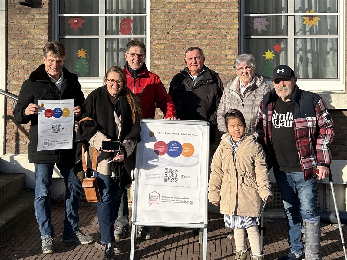 Protagonisten aus den App-Videos und Projektverantwortliche vom Förderverein Hansestadt Grieth während sie die Hansestadt mit der Grieth-App auf ihrem Smartphone erkunden. Foto: Förderverein Hansestadt Grieth