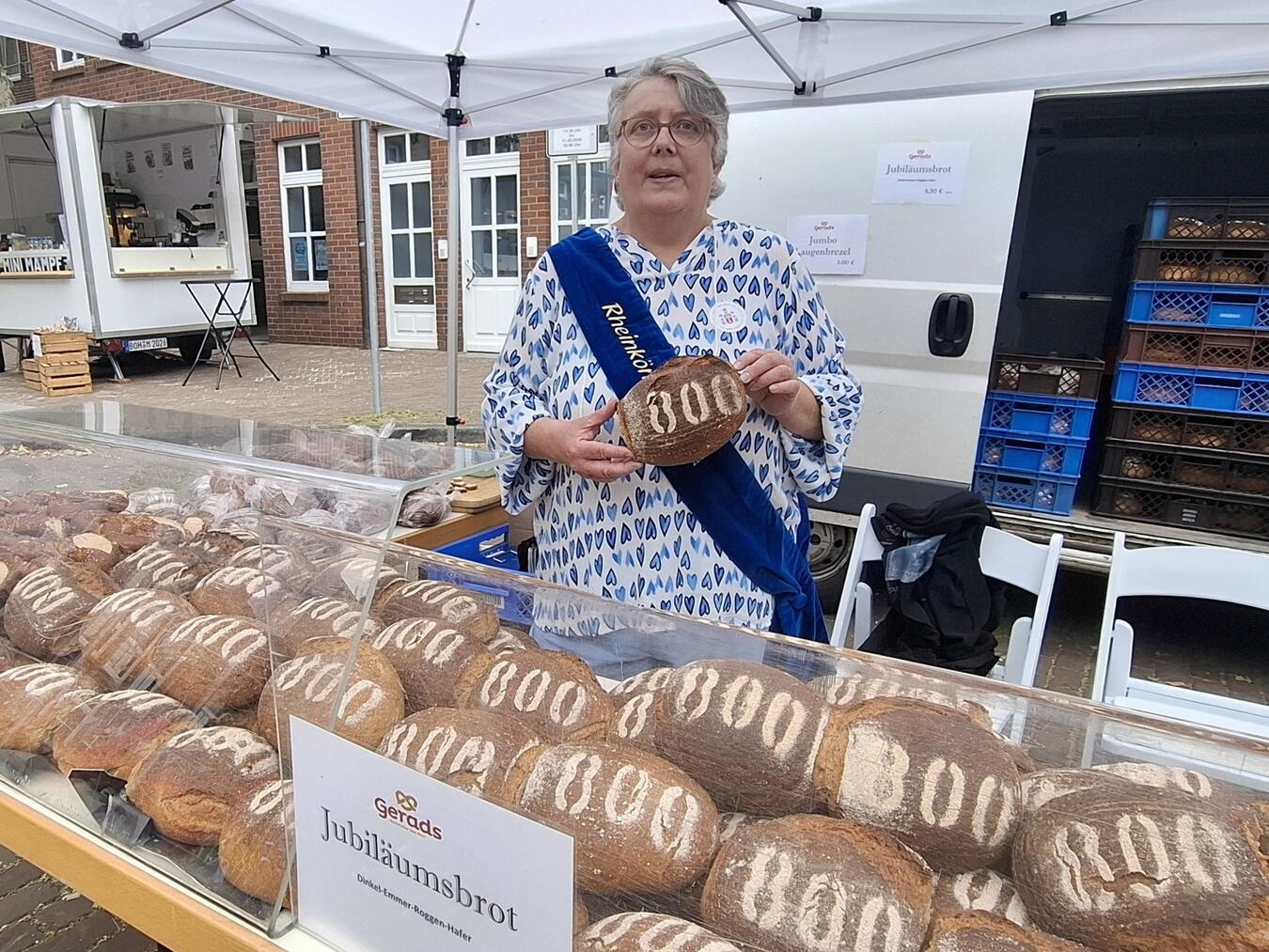 "Rheinkönigin Jutta Green verkauft Jubiläumsbrot auf Sommermarkt in Rees"