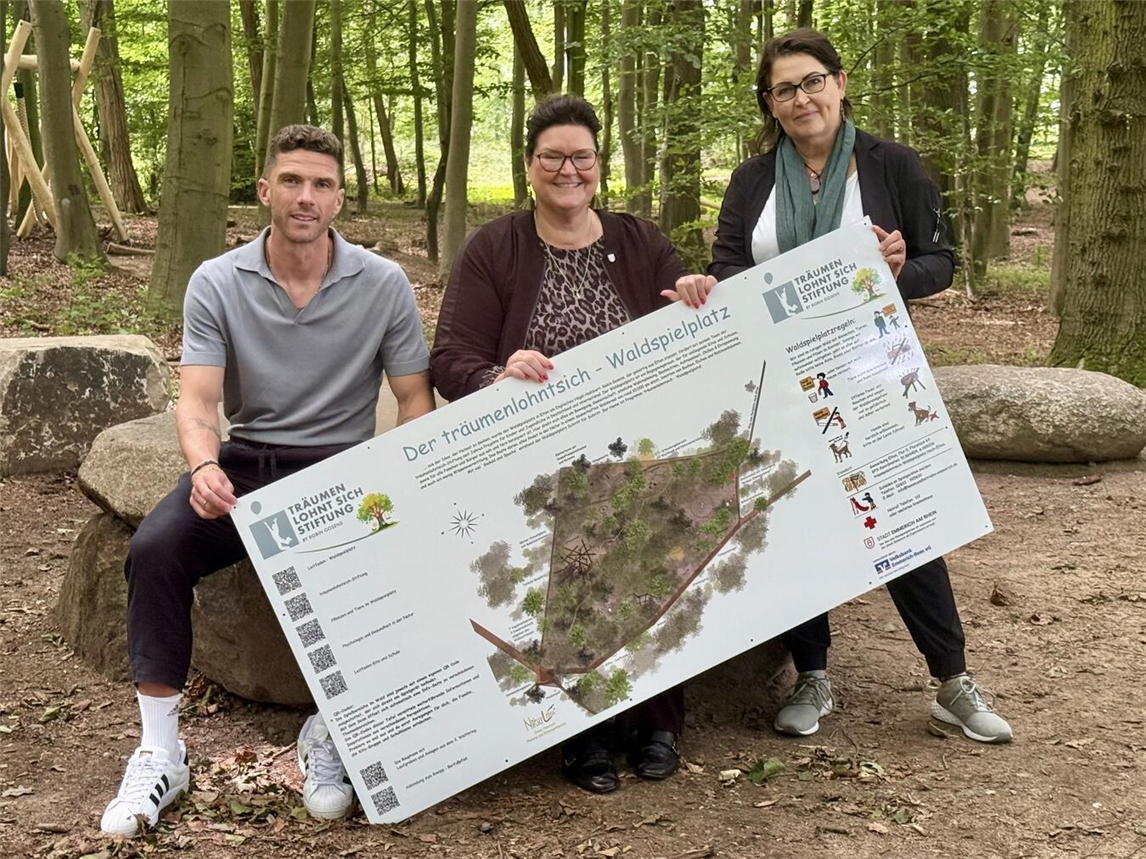 Robin Gosens, Emmerichs Bürgermeisterin Claudia Lindlahr und Landschaftsarchitektin Jenny Humrich haben den neuen Waldspielplatz in Hochelten gemeinsam vorgestellt. Hier sitzen beziehungsweise stehen sie im "Steinkreis", einer Art Waldschule. NN-Foto: SP