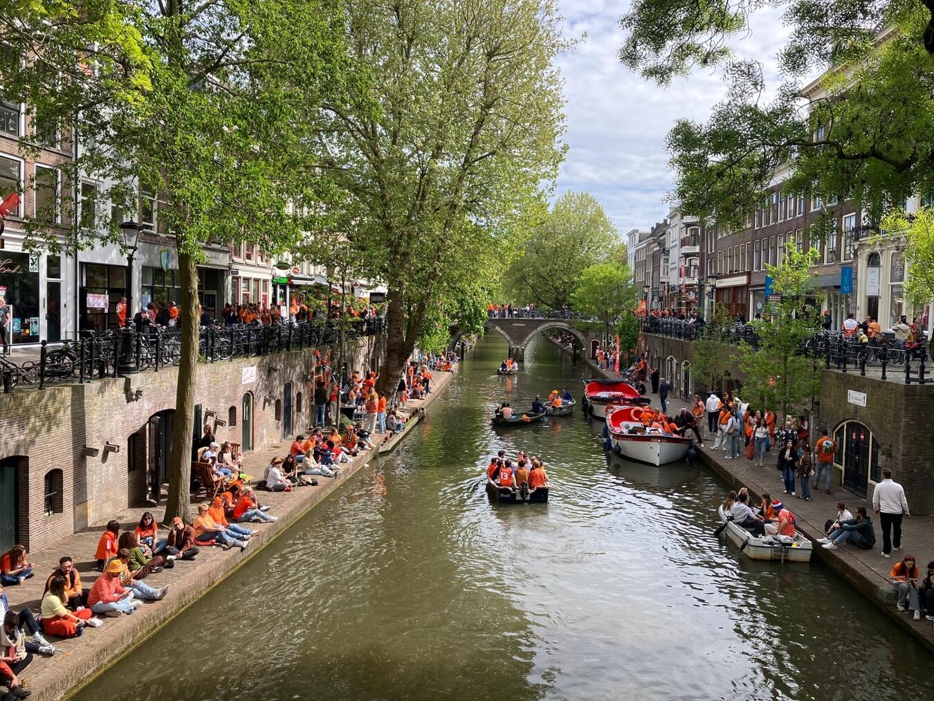 Gracht in Utrecht am Königstag: Menschen in Orange feiern auf Booten.