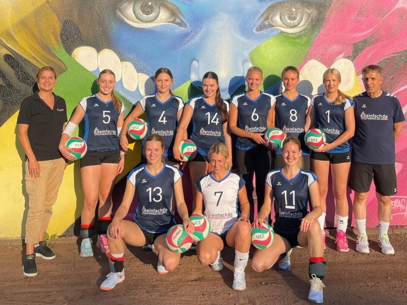 Sarah Bousart von den Stadtwerken Geldern (links) übergibt die neuen Trikots an das Team des VCE sowie ihren Co-Trainer „Ille“ van Meegen (r.). Foto: VCE Geldern