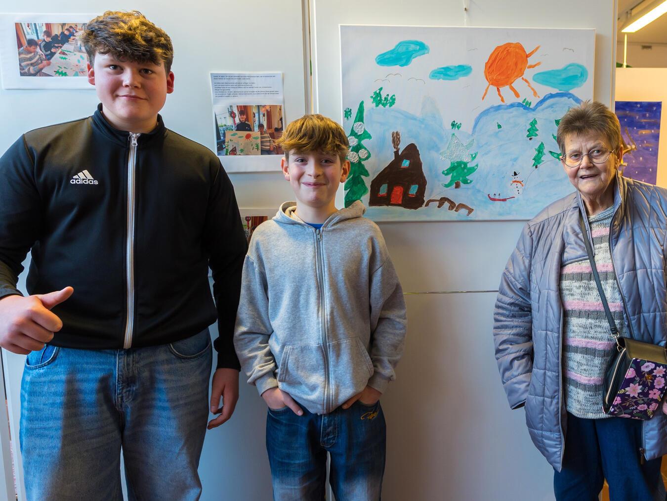 Schüler präsentieren zusammen mit einer Seniorin ein gemeinsames Bild in der Ausstellung.