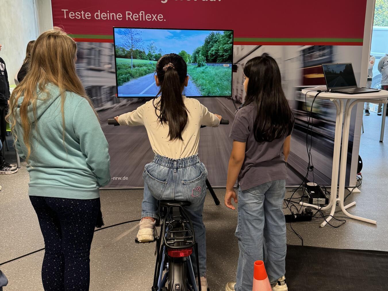 Schülerinnen testen die Statiion „Fahrradsimulator“.