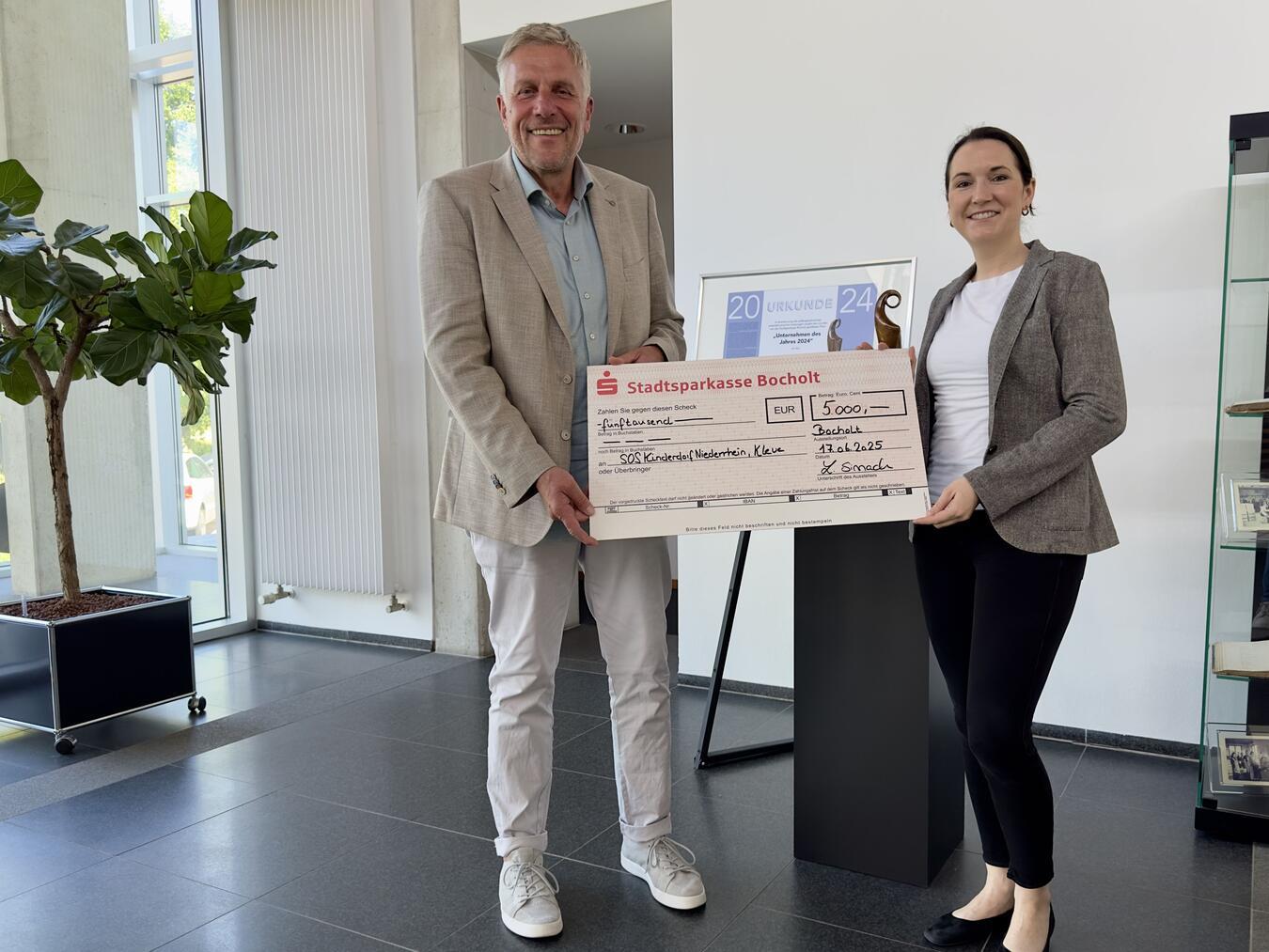 SOS-Einrichtungsleiter Peter Schönrock nimmt den Spendenscheck von Sinnack-Geschäftsführerin Lena Sinnack in Empfang. Foto: SOS-Kinderdorf Niederrhein/ Katrin Wißen