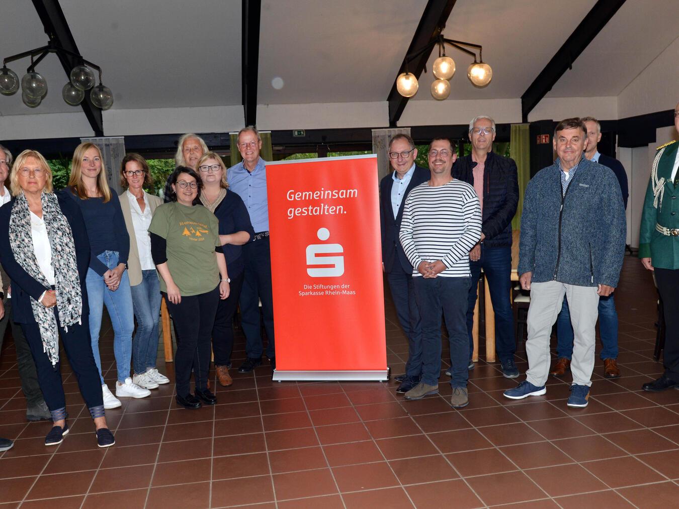 Spendenübergabe an Reeser Vereine: Kuratoriumsmitglieder Bodo Wißen (r.), Sebastian Hense (7. v. r.) und Stiftungsvorstand Ludger Braam (l.) im Bürgerhaus Bienen. Foto: Stiftungen der Stadtsparkasse Emmerich-Rees/SKRM
