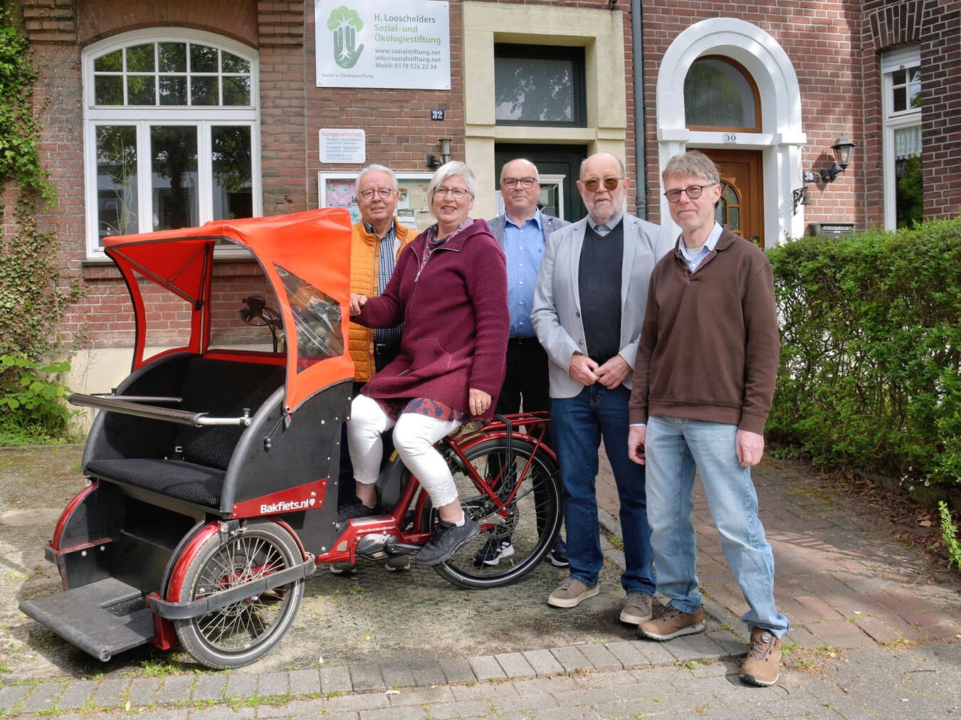 Spendenübergabe in Kleve: Teilnehmer des Rikscha-Projekts mit Scheck, darunter Petra Bossmann und Herbert Looschelders.