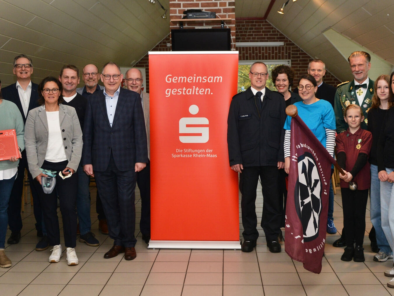 Spendenübergabe: Kuratoriumsmitglieder Bodo Wißen (4. v. l.) und Sebastian Hense (8. v. l.) sowie Stiftungsvorstand Ludger Braam (9. v. l.) mit Vertretern der Reeser Vereine im Platzhaus des SV Haldern. Foto: Stiftungen der Stadtsparkasse Emmerich-Rees/Sparkasse Rhein-Maas