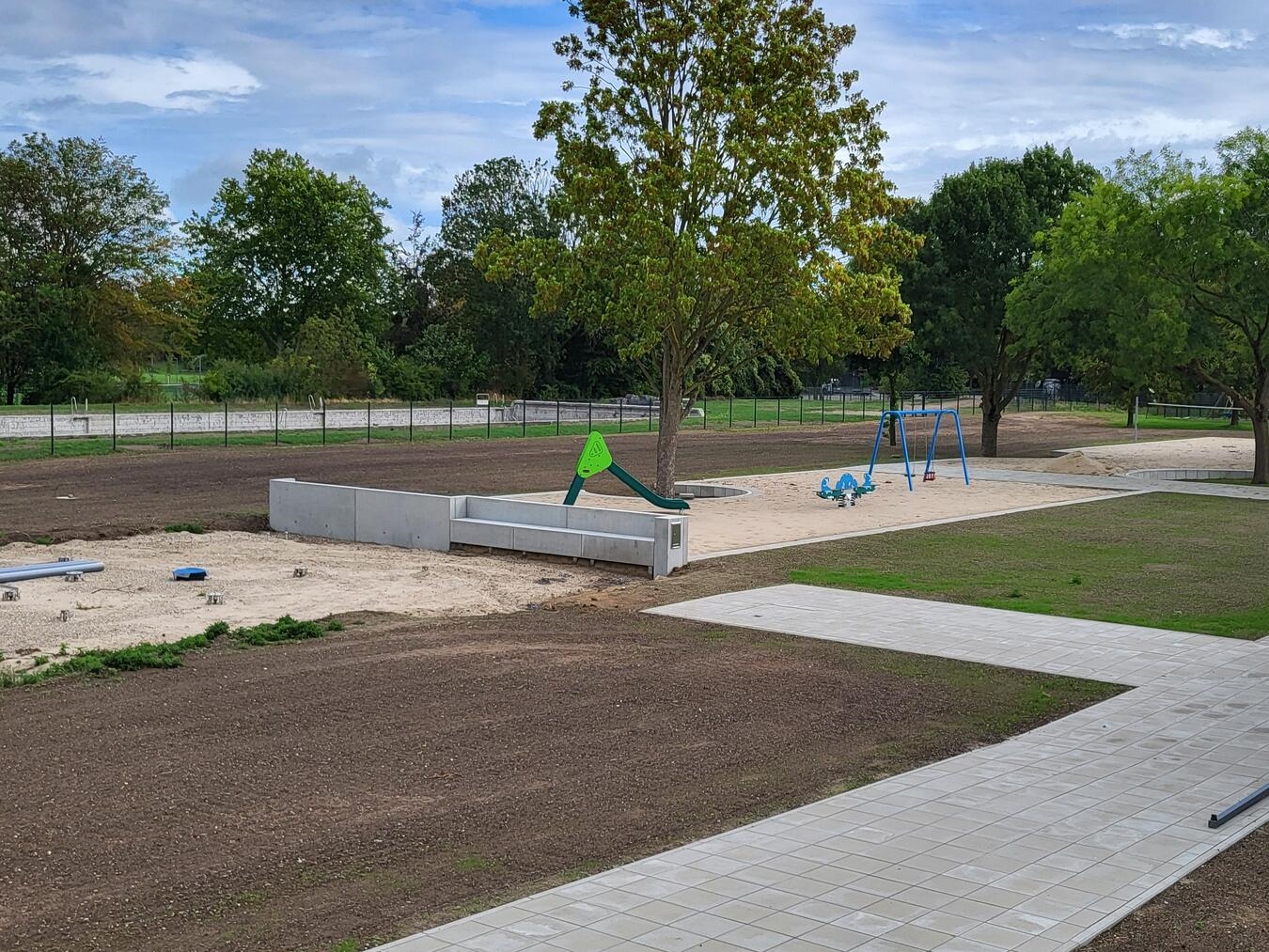 Wasser-Freizeit Rees: Erster Bauabschnitt fertig – so geht es mit Freibad und Spraypark weiter Spielplatz mit Volleyballfeld, Fundamente für Spraypark links, altes Schwimmbecken im Hintergrund, Fertigstellung Freizeitpark.
