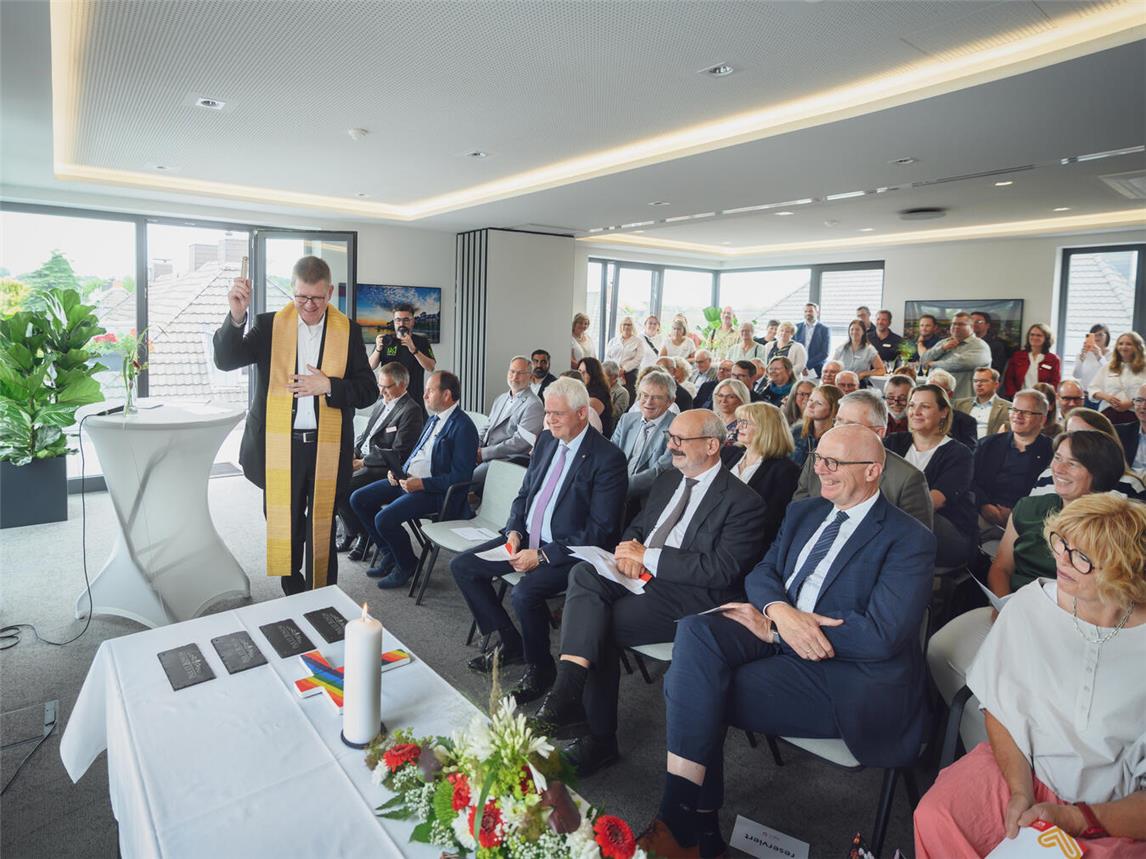 Stellvertretend für die kompletten Räumlichkeiten der Caritas segnete Propst Johannes Mecking (l.) vier „Pax et Bonum“-Schiefertafeln ein. In der ersten Reihe sitzen von rechts nach links: Kalkars Bürgermeistern Dr. Britta Schulz, Landrat Christoph Gerwers, Kleves Bürgermeister Wolfgang Gebing, Landtagsabgeordneter Dr. Günther Bergmann, Architekt Johannes Peeters und Vorstand Rainer Borsch. Foto: Markus van Offern/Caritasverband Kleve