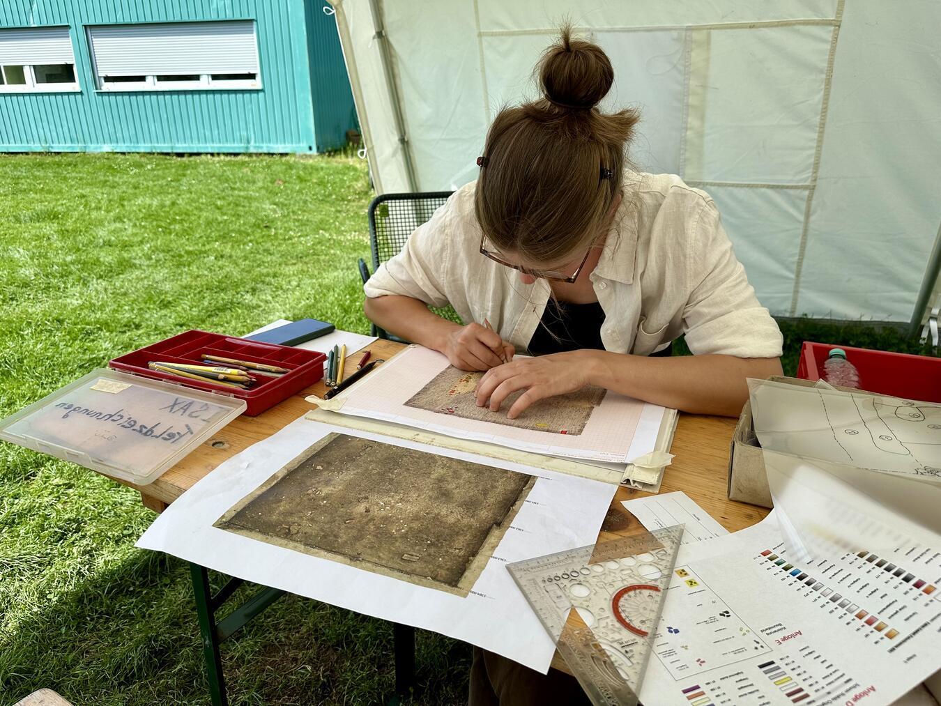 Studentin Pia Pfaff zeichnet ein abfotografiertes Boden-Profil farblich passend zum Befund und der Konsistenz des Bodens nach.