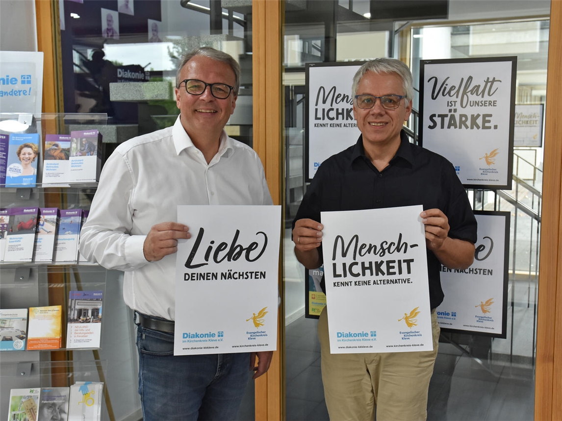 Superintendent Pfarrer Robert Arndt (l.) und Diakonie-Geschäftsführer Pfarrer Joachim Wolff mit den Plakaten. Foto: Evangelischer Kirchenkreis Kleve