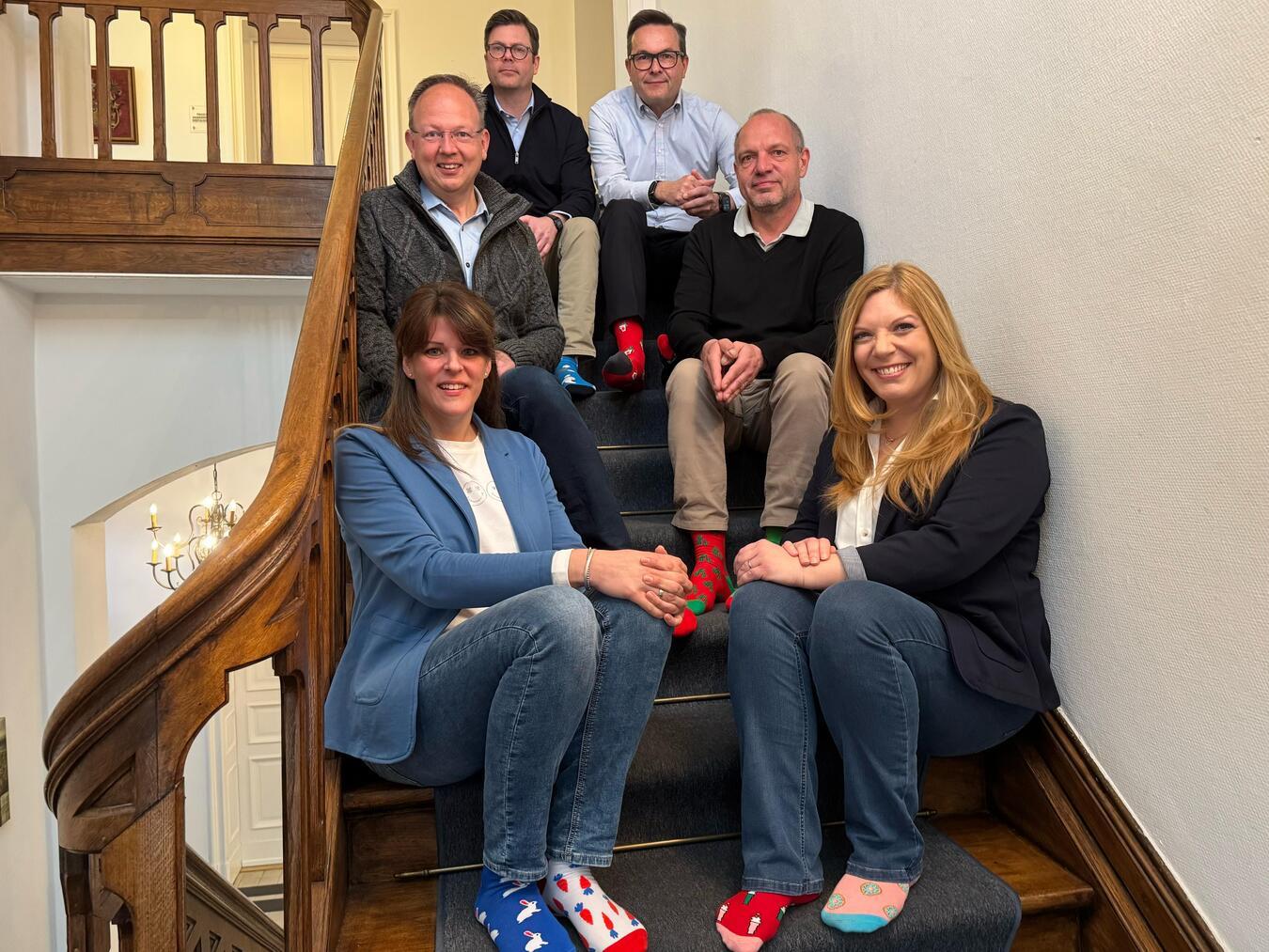 Tanja Angenendt (v.l., Inklusionsbeauftragte), Nadine Schönfelder (v.r., Gleichstellungsbeauftragte), Markus Grönheim (M.l., zweiter Beigeordneter), Thomas Knorrek (M.r., Kämmerer), Tim van Hees-Clanzett (o.l., erster Beigeordneter) und Sven Kaiser (o.r., Bürgermeister) beteiligen sich an der Socken-Aktion zum Welt-Down-Syndrom-Tag.Foto: Stadt Geldern/Gossens