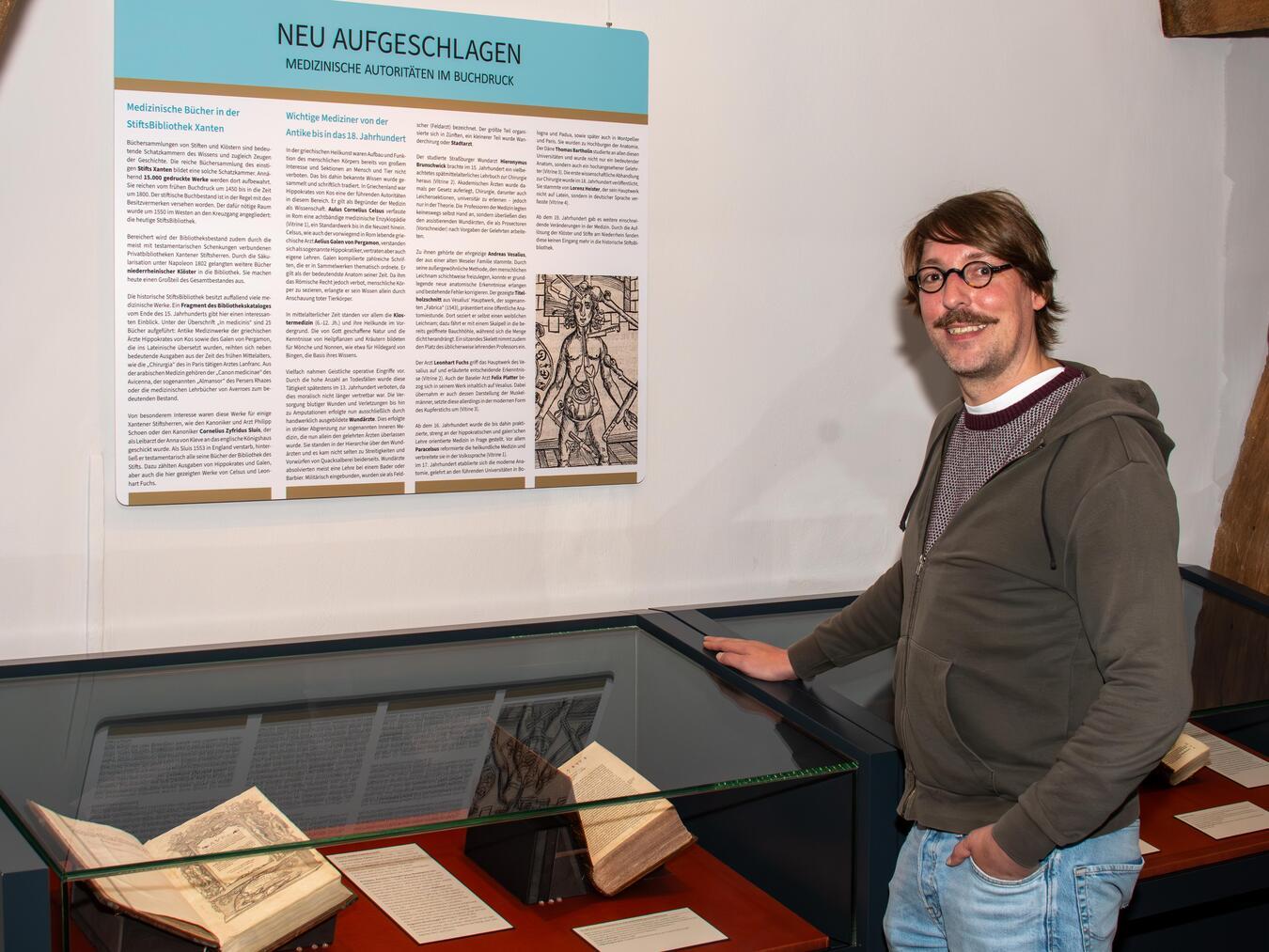 Thomas Hensolt freut sich, einige der Bücher aus der Stiftsbibliothek in den Vitrinen der Ausstellung „Neu aufgeschlagen“ präsentieren zu können. Foto: Bischöfliche Pressestelle / Christian Breuer
