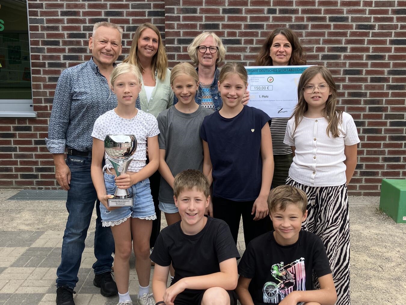 "Pokalübergabe an Brüder-Grimm-Grundschule Issum, Auszeichnungsempfang, Schulvertreter mit Urkunde, Erfolgsmoment, Foto: privat"