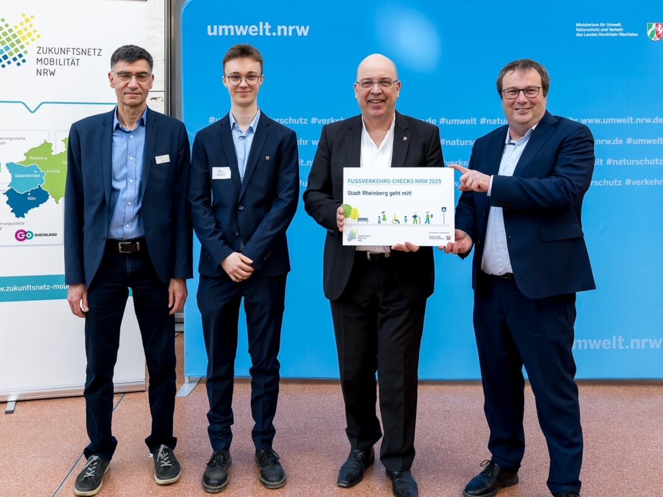Ulrich Hornig (Zukunftsnetz Mobilität), Jonas Gaßling (Mobilitätsmanager Stadt Rheinberg), Stephan Pfeffer (Erster Beigeordneter Stadt Rheinberg) und Minister Oliver Krischer (Ministerium für Umwelt, Naturschutz und Verkehr des Landes Nordrhein-Westfalen) bei der Urkundenübergabe. Foto: go.Rheinland GmbH / Smilla Dankert