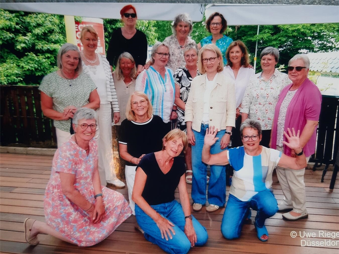 Gruppenfoto von 16 Frauen in drei Reihen, lächelnd; Namen und Fotograf Uwe Rieger erwähnt; Klassentreffen 2023.