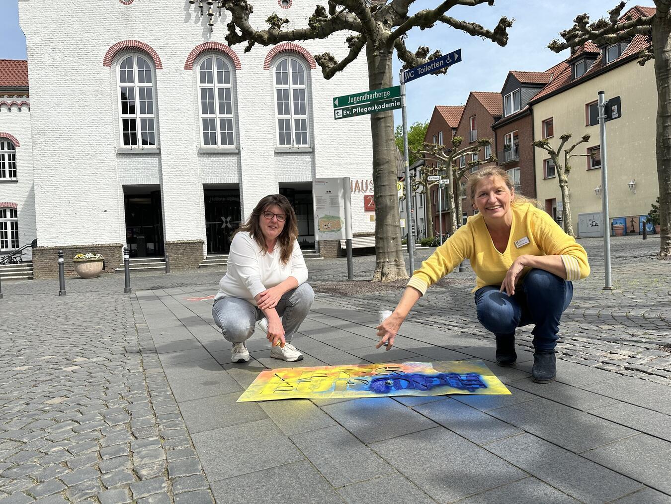 Wie soll Europa heute und morgen aussehen? Valérie Petit (l.) und Carolin Schwartz (r.) sprühen mit umweltschonender Sprühkreide das Kampagnen-Motto „Let’s Europe“ auf den Boden. Morgen erwarten sie einen spannenden Austausch. NN-Foto: SP