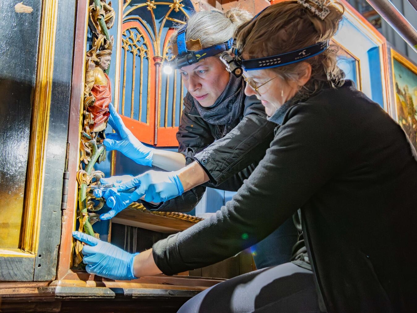 Verena Ebel (links) und Sarah Grimberg setzen die Einzelteile des Altares mit größter Sorgfalt zusammen. Nun ist das Werk aus dem frühen 16. Jahrhundert wieder in voller Pracht zu bewundern. Fotos: Bischöfliche Pressestelle / Christian Breuer