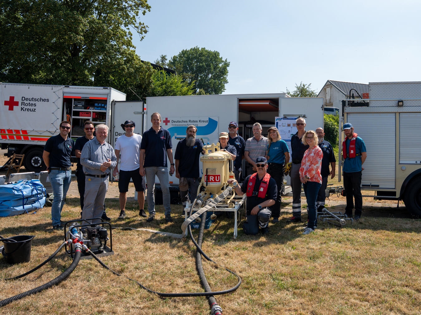Vertreterinnen und Vertreter des Kreises Wesel informierten sich beim DRK-Kreisverband Niederrhein über die Möglichkeiten der mobilen Trinkwasseraufbereitung im Bevölkerungsschutz. Mit dabei waren Janina Schmidt-Jakisch (Gesundheitsamt Kreis Wesel), Frank Brändel (Leiter Fachdienst Sicherheit und Ordnung), Sven Rissel (Krisenmanagement) sowie Niklas Killewald (Leiter der Kreisleitstelle Wesel). Ebenfalls auf dem Bild sind Vertreter des Präsidiums des DRK Kreisverbandes Niederrhein sowie Mitglieder der Fachgruppe Technik & Sicherheit und der TWA-Gruppe (Trinkwasseraufbereitung) zu sehen. Foto: Silas Thekook/DRK