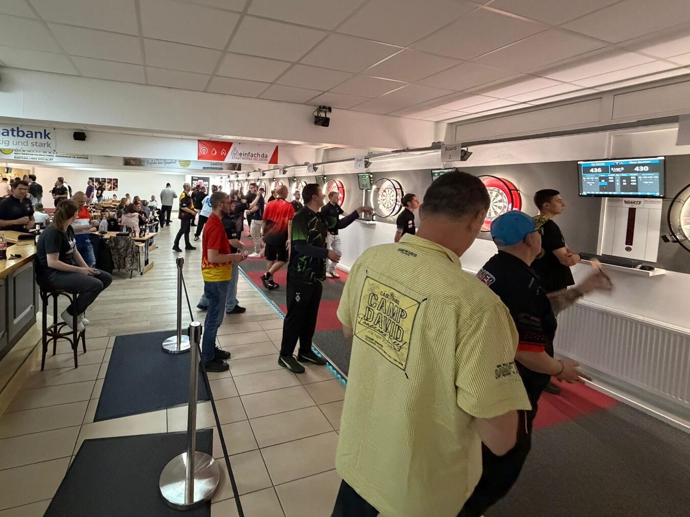 Gelderner Dartclub feiert Comeback: Vom drohenden Aus zum Aufstieg in die Regionalliga "Vollbesetzte Dart-Arena in Geldern während GDC-Turnier, Zuschauer und Spieler vereint"