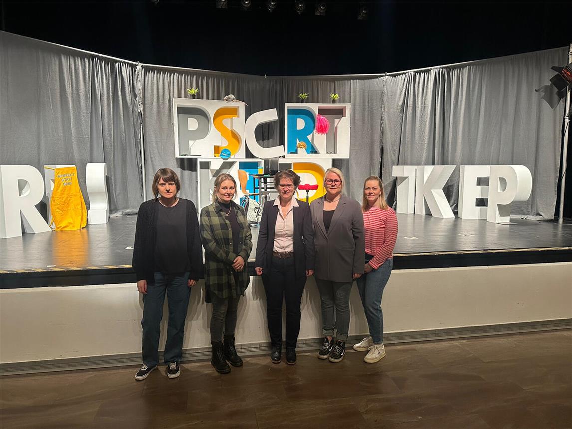 Vor der Theaterbühne stehen Tina Deipenwisch (Caritasverband Moers-Xanten), Maike Holthuis (Fachbereich Jugend, Stadt Rheinberg), Iris Itgenshorst (Sozialdezernentin Stadt Rheinberg), Ricarda van den Berg (Koordinatorin für das Netzwerk Kinderschutz Stadt Rheinberg) und Sandra Handwerk (Caritasverband Moers-Xanten). Foto: Stadt Rheinberg