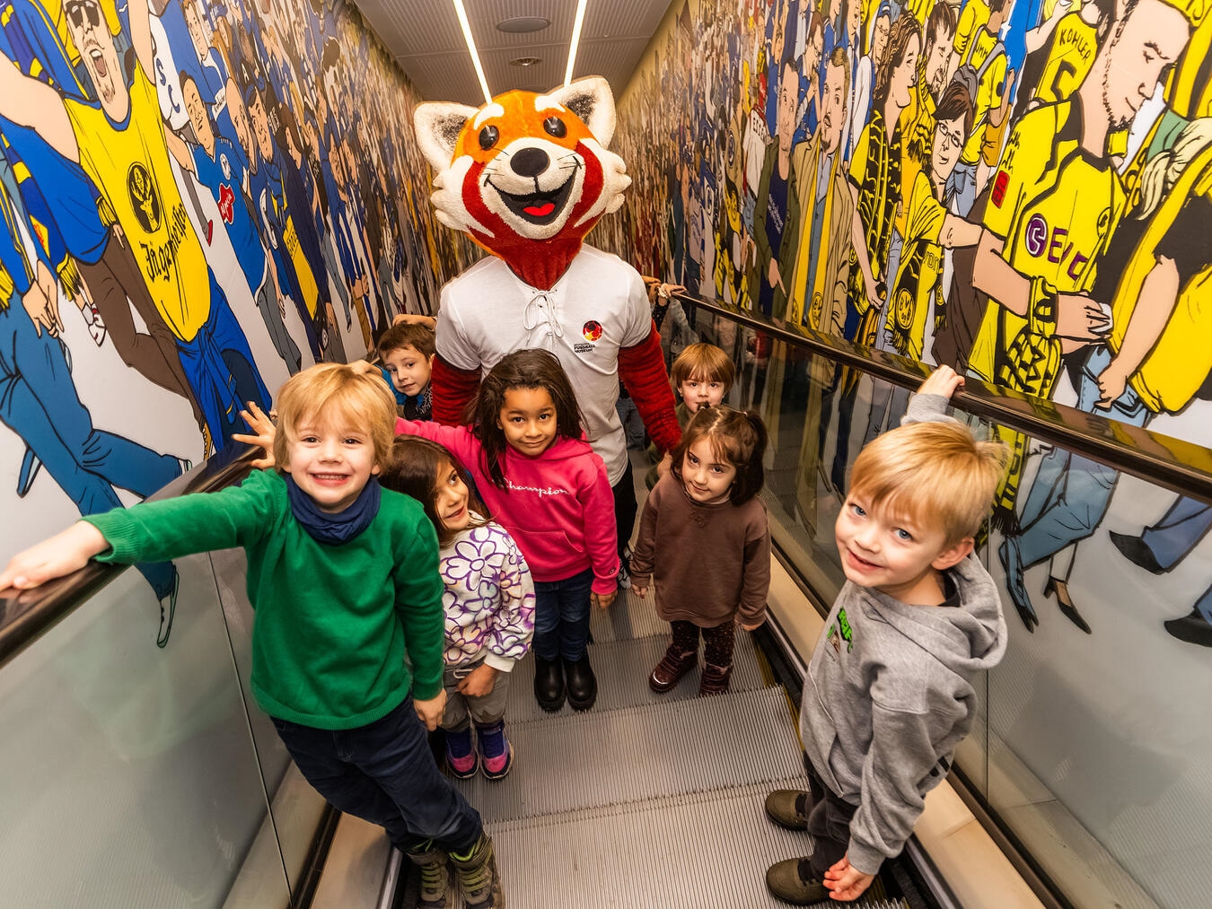 Vorbei an den Fans: Maskottchen Rio fährt mit Kindern nach oben in die Dauerausstellung. Fotos: Stephan Schütze