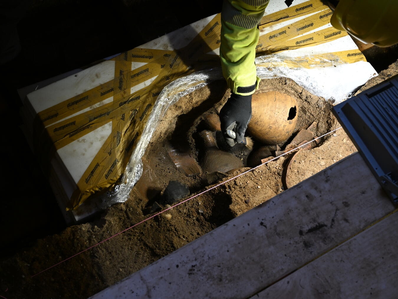 Vorsichtig werden die Funde auf der Brunnensohle freigelegt. Foto: Dr. Mathias Lange / LVR-Archäologischer Park Xanten