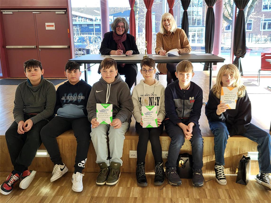 Während Andrea Joosten (hinten l.) und Christiane Feldmann die neue Kooperationsvereinbarung unterzeichnen, werden die Finalisten des Vorlesewettbewerbs ausgezeichnet: (v. l.) Elias Witting, Silvan Tuku, Valentin Derksen, Lena Rau, Enno Flamm und Hailee Rubens. NN-Foto: MB