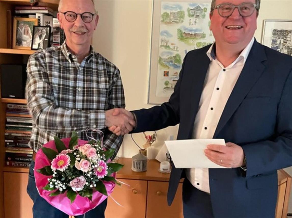 Weezes Bürgermeister Georg Koenen (r. )bedankt sich bei Johannes van Hall mit einem Blumenstrauß und einem Gutschein für seine 30jährige Tätigkeit in der Macherey-Stiftung. Foto: privat
