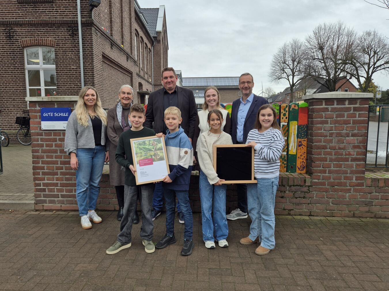 Westenergie Kommunalmanager Frithjof Gerstner (r.) verleihen gemeinsam mit der stellvertretende Bürgermeisterin Renate Fürtjes (2.v.l.) und Klimaschutzmanagerin Lisa Gülleken (l.) den Klimaschutzpreis 2025 an die Mariengrundschule.Foto: Gemeinde Kerken