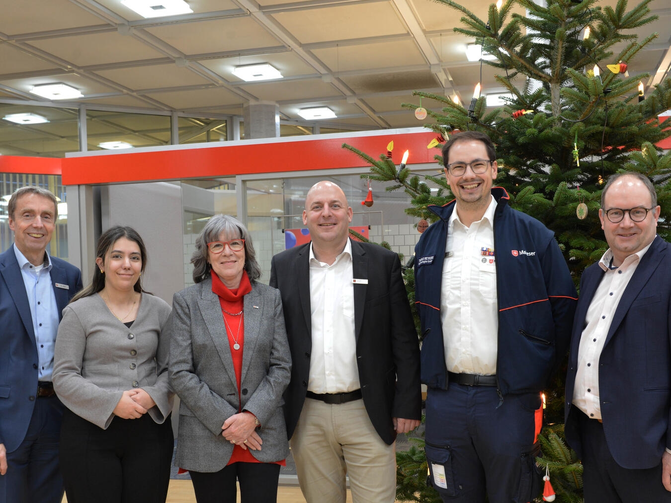 Wilfried Röth (links), Andreas Meder (rechts) und Andreas Servas (3. von rechts) überraschen mit der Sparkassen-Weihnachtsspende die Johanniter aus Emmerich (vertreten durch Rojin Adar, 2.v.l.), Maria Anna Kaußen (für den DRK-Kreisverband, 3.v.l.) und Thomas Reykers (Malteser Kevelaer, 2.v.r.). Foto: Sparkasse Rhein-Maas