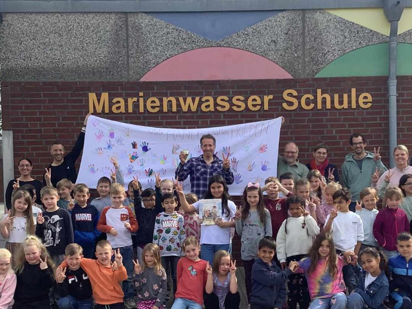 "Willi Weitzel besucht Weezer Grundschulen, lächelnd mit Schülern im Klassenzimmer. Foto: VDK Weeze"