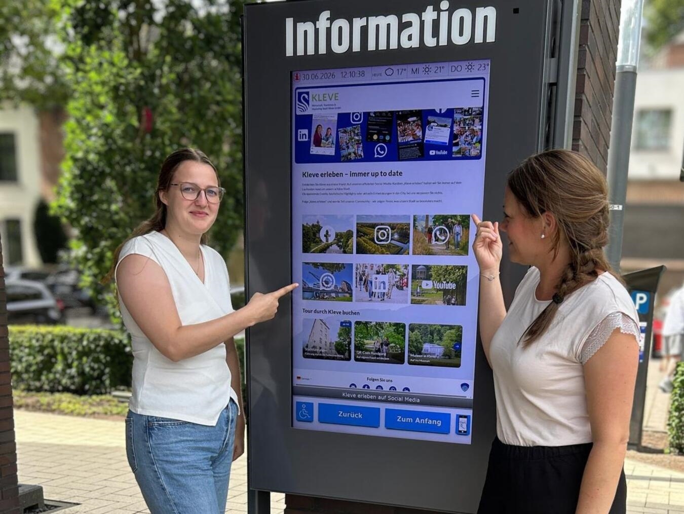 "WTM-Mitarbeiterinnen präsentieren Social Media-Seite mit Links, Büro-Umgebung, Teamarbeit, digitale Vernetzung"