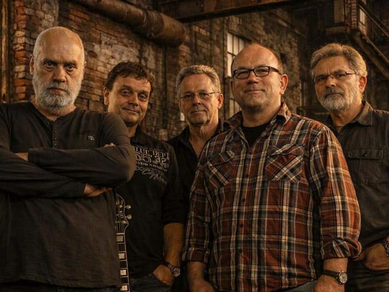 "Red Rooster BluesGroup Bandmitglieder posieren mit Instrumenten: Bluesharp, Gitarren, Bass und Schlagzeug"