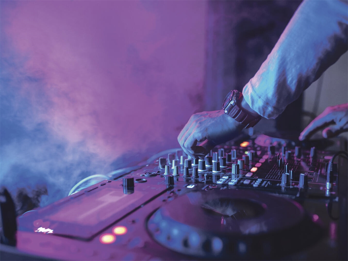DJ legt auf Singleparty der Lebenshilfe auf, bunte Lichter und Tanzende. Foto: Adobestock