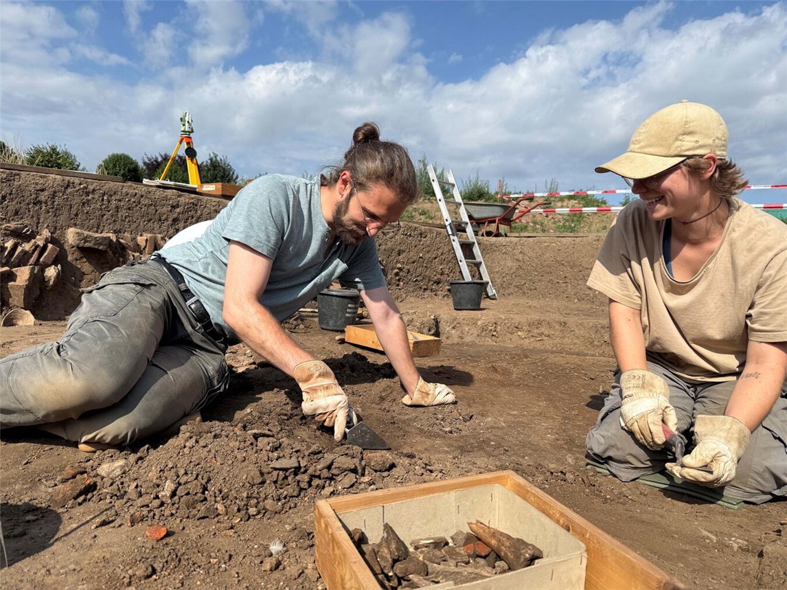 "Zwei Studenten bei archäologischer Ausgrabung in Xanten, Sommerakademie, Fundkiste und Kelle, Foto von Angelina Witt"